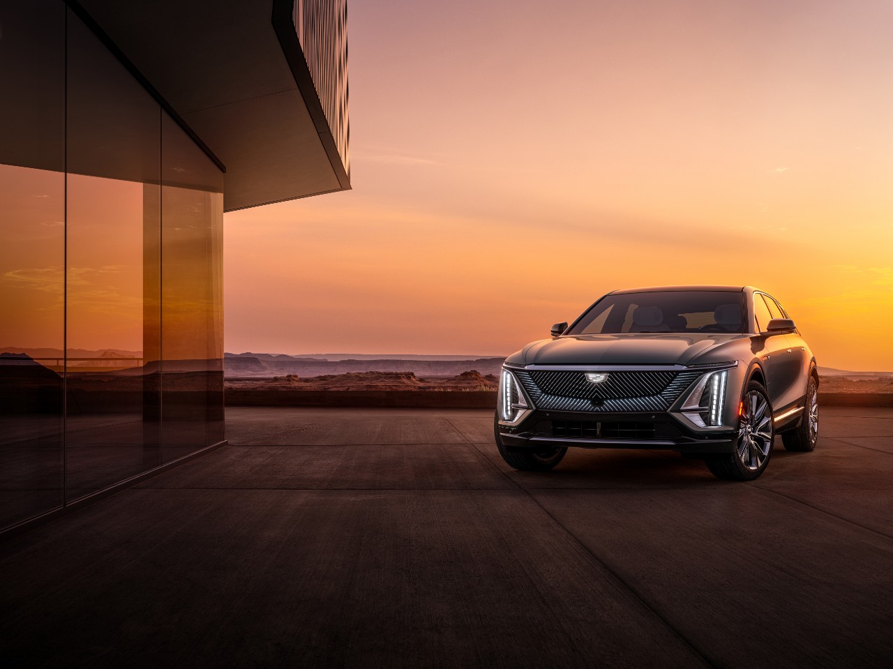 Cadillac LYRIQ in Satin Steel Metallic parked next to a house at sunset - Midway Group inventory